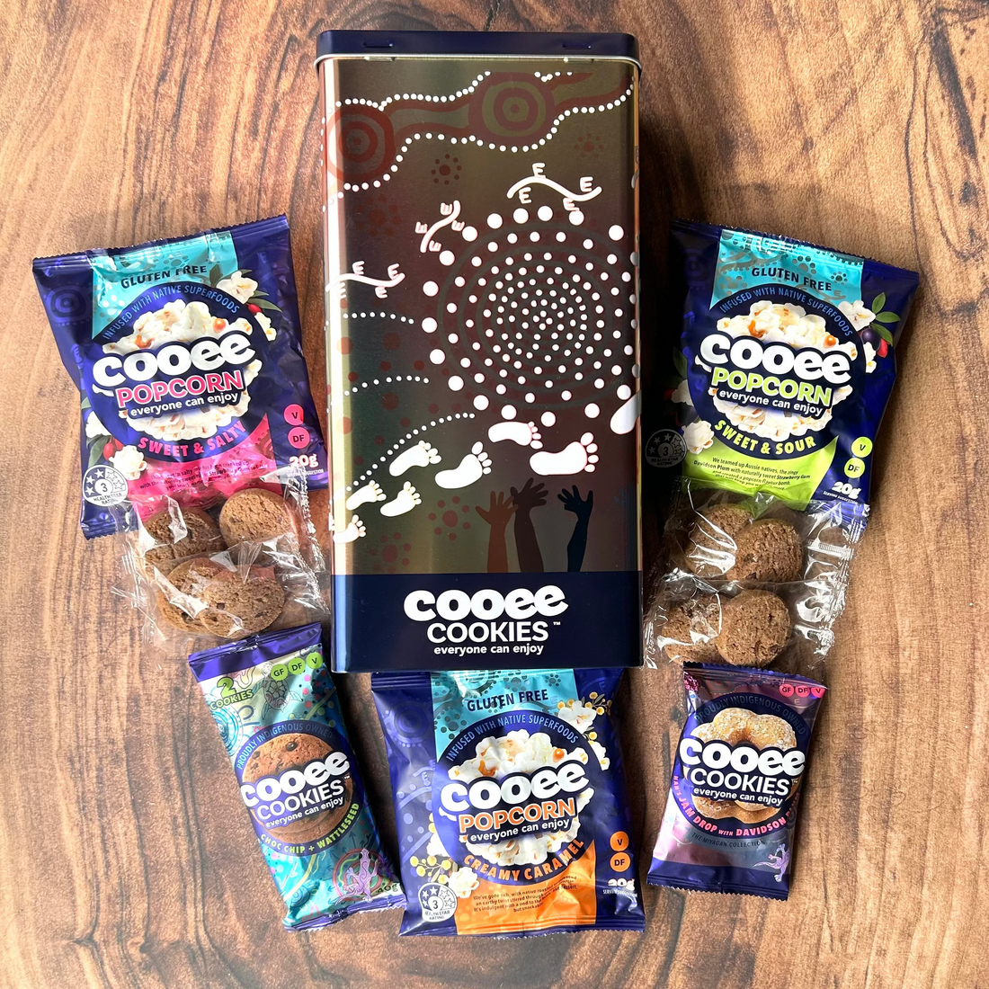 Naidoc Gift tin, Cooee Cookies and Popcorn packaging on a wooden surface